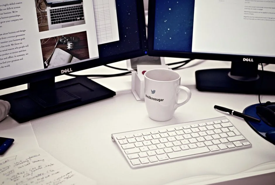Two monitors on a desk, displaying web design in a contemporary office environment.